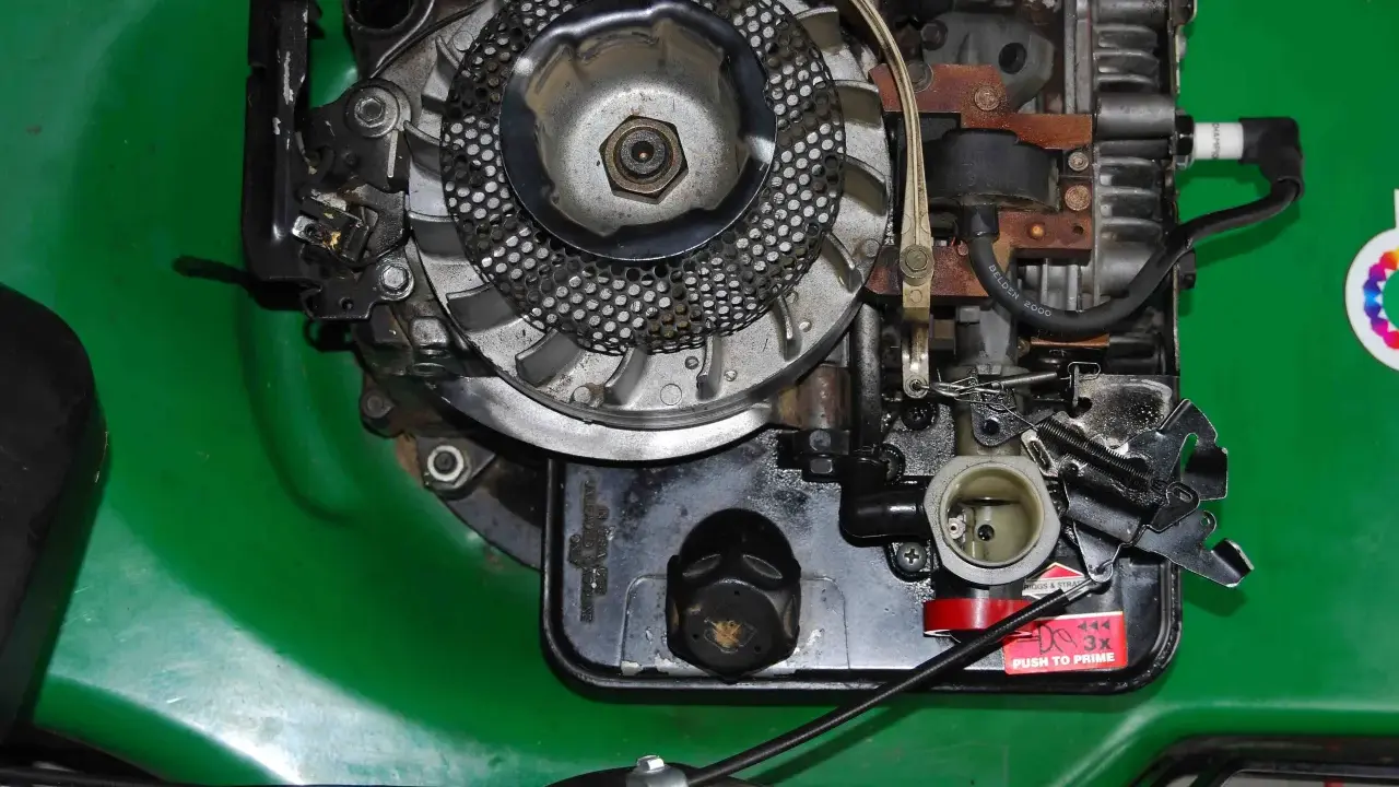 Silnik kosiarki Briggs & Stratton z widocznym gaźnikiem i świecą zapłonową. Podpowiadamy, jak ustawić zapłon w kosiarce Briggs & Stratton.