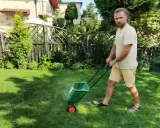 Mężczyzna z dredami używa zielonego siewnika do nawozu na trawniku. Idealny siewnik do nawozu na trawnik ułatwia pielęgnację ogrodu.