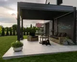 Nowoczesna pergola z zacienieniem, meble wypoczynkowe i pies. Idealne miejsce do relaksu, zastanawiasz się, czym zabezpieczyć pergole?
