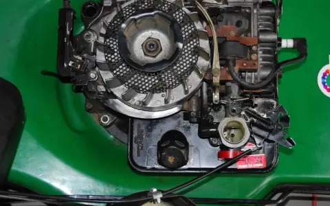 Silnik kosiarki Briggs & Stratton z widocznym gaźnikiem i świecą zapłonową. Podpowiadamy, jak ustawić zapłon w kosiarce Briggs & Stratton.