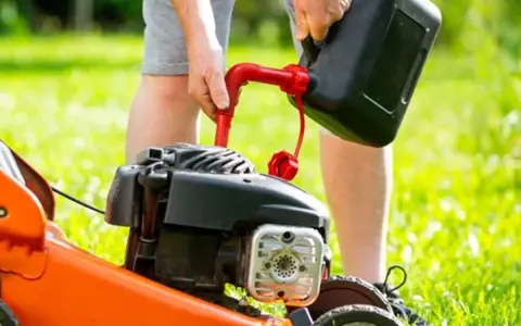 Osoba nalewa paliwo do kosiarki Briggs & Stratton. Użyj benzyny bezołowiowej 95.