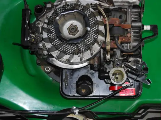 Silnik kosiarki Briggs & Stratton z widocznym gaźnikiem i świecą zapłonową. Podpowiadamy, jak ustawić zapłon w kosiarce Briggs & Stratton.