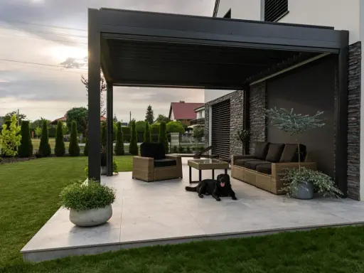 Nowoczesna pergola z zacienieniem, meble wypoczynkowe i pies. Idealne miejsce do relaksu, zastanawiasz się, czym zabezpieczyć pergole?