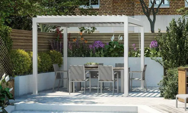 Nowoczesna pergola z jadalnianym zestawem w ogrodzie, otoczona kwitnącymi roślinami i zielenią. Idealne miejsce na relaks.