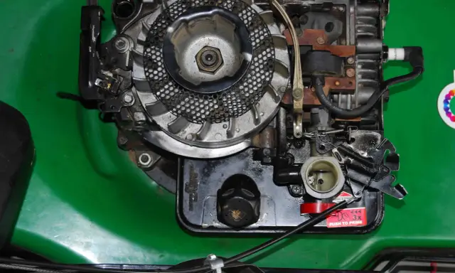 Silnik kosiarki Briggs & Stratton z widocznym gaźnikiem i świecą zapłonową. Podpowiadamy, jak ustawić zapłon w kosiarce Briggs & Stratton.