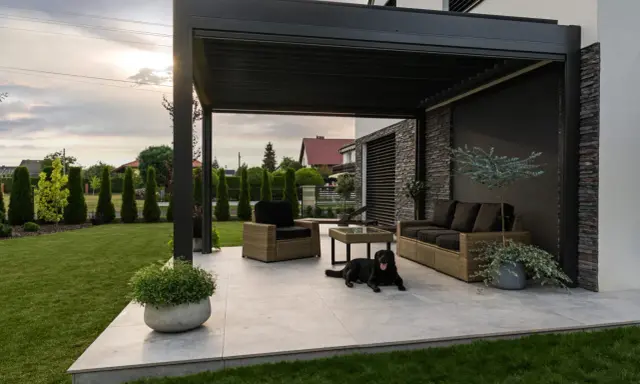 Nowoczesna pergola z zacienieniem, meble wypoczynkowe i pies. Idealne miejsce do relaksu, zastanawiasz się, czym zabezpieczyć pergole?