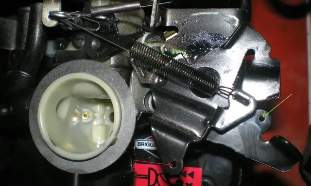 Mechanizm kosiarki Briggs & Stratton. Pokazuje, jak założyć sznurek do kosiarki, mocując go do dźwigni gazu.