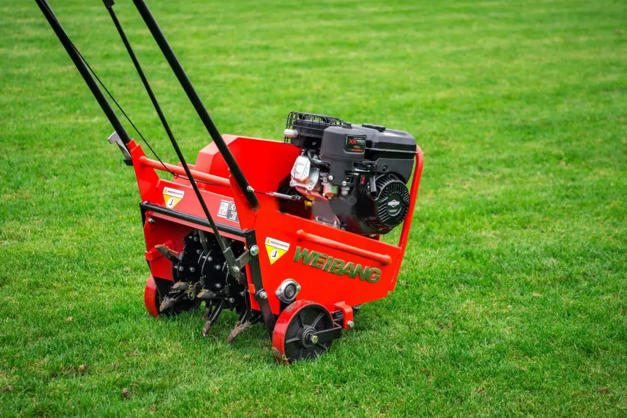 Czerwony aerator Weidemann na zielonej trawie. Idealny czas na aerację trawnika, aby zapewnić jej zdrowy wygląd.